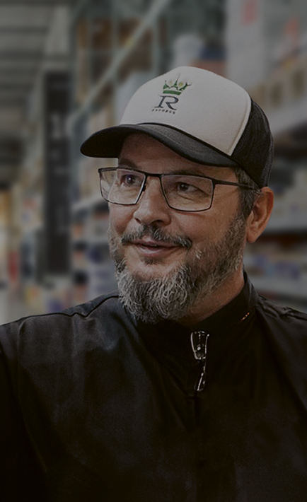 A man with a beard and glasses is wearing a hat with a logo on it.