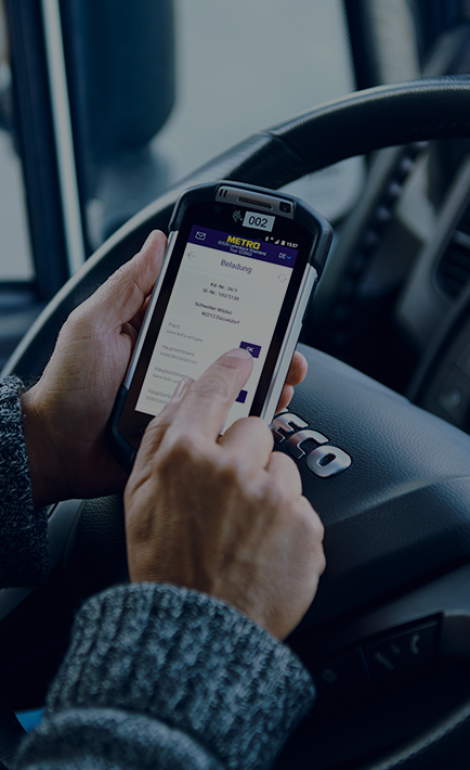 A person is holding a cell phone showing the METRO App while inside a vehicle.