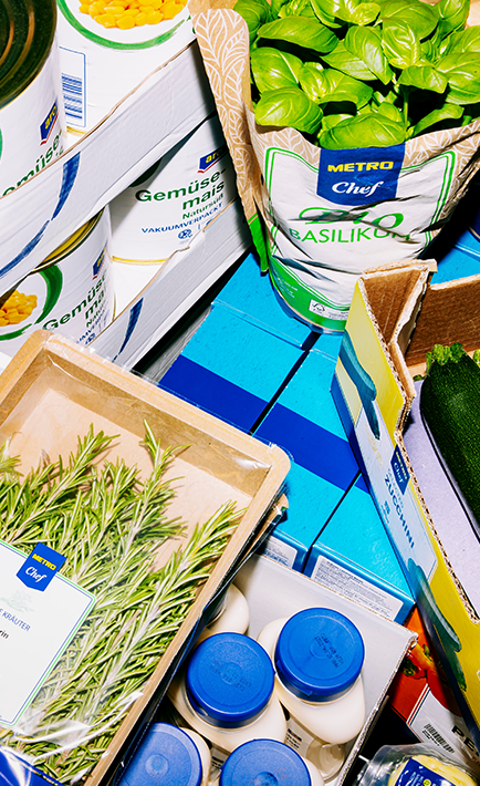 The image features a variety of herbs and spices, including basil and rosmary. These herbs and spices are displayed in an assortment of containers, such as bottles and a wooden crate.