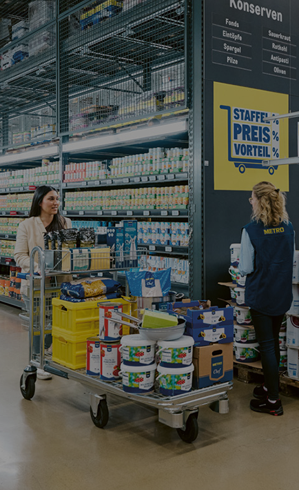 A woman is shopping at a store, pushing a cart full of items.