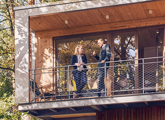 Anne Hildebrand and Raphael Fellmer talking to each other on a balcony (photo)